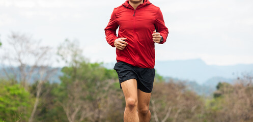 Fototapeta premium Trail runner man running on rocky mountain. Athlete jog exercising outdoor for healthy. Confident and powerful marathon man running workout and cardio. Sport and Lifestyle concept.