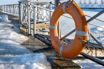 Orange lifebuoy on the fence at the pier. Saving life on a sea voyage. Rescue operation in an emergency.