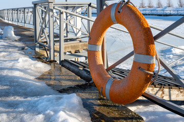 Orange lifebuoy on the fence at the pier. Saving life on a sea voyage. Rescue operation in an...