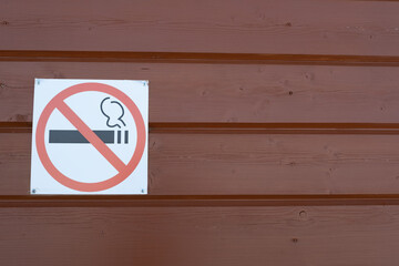 A sign banning smoking on a wooden wall. Warning about the dangers of smoking.