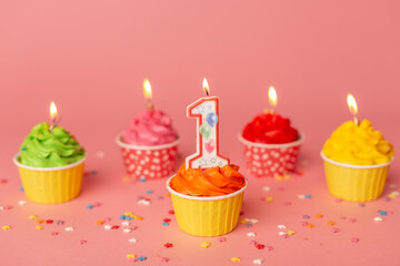 First bithday cake. Number 1 candle in a cupcake among colorful cakes on the pink background