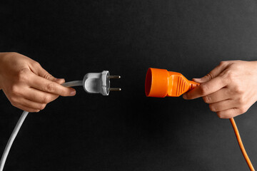 electricity, energy and power consumption concept - close up of woman inserting plug into socket...