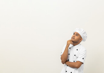 Young handsome asian man chef in uniform standing looking at blank space and thinking menu on isolated background. Cooking indian man Occupation chef or baker People in kitchen restaurant and hotel.