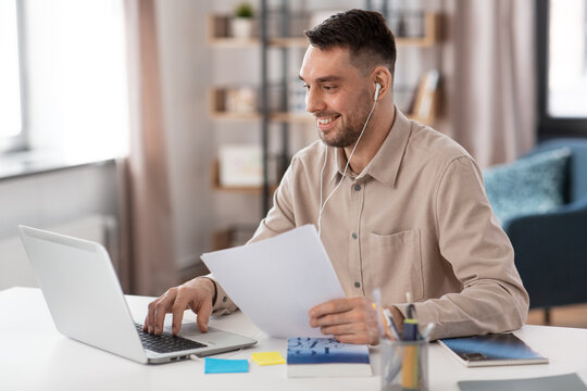 distance education, school and remote job concept - happy smiling male teacher or student with laptop computer and earphones working or learning at home office