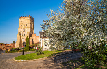 Fototapeta na wymiar Spring scenery of Lutsk Castle with Lubart Tower. Blossoming tree in foreground. Lutsk, Ukraine