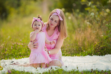 mother and daughter in pink dresses sit on a white blanket