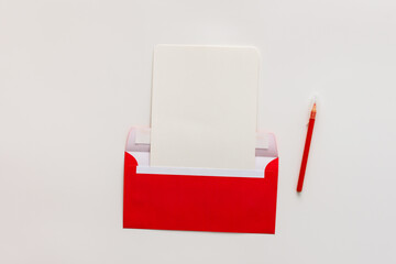 Red envelope with blank paper and pen, greeting card or invitation mockup, top view, copy space