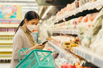 Young woman wearing medical mask shopping in supermarket during coronavirus pneumonia outbreak. Protection and prevent measures while epidemic time..