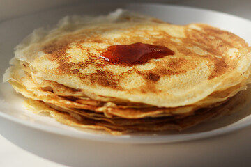 Slavic thin fried pancakes with a crispy golden crust in a stack of maple syrup