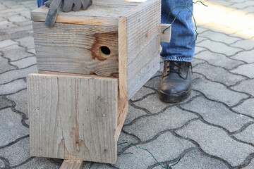 Repairing of natural finish birdhouse before mounting in a garden to support wildlife. Birds support to decrease pest in garden. 