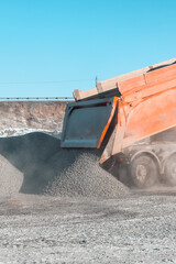 trucks carry and unload crushed stone at an asphalt concrete plant, which is needed for road construction