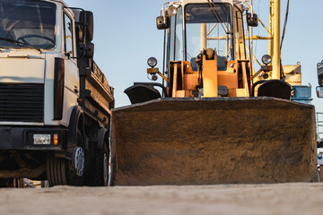 Heavy wheel loader with a bucket at a construction site. Equipment for earthworks, transportation and loading of bulk materials - earth, sand, crushed stone.