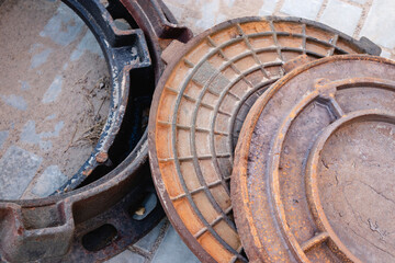 New cast iron manholes prepared for installation at the construction site. Hatches with covers lie on the paving slabs.