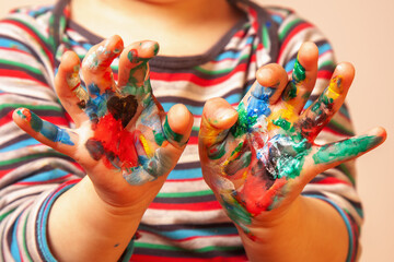 Funny portrait of beautiful young child girl with painting colorful hands. Selective focus.
