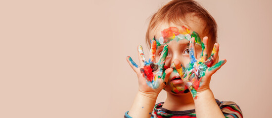 Funny portrait of beautiful young child girl with children's face makeup and painting colorful hands. Copy space for text or design.