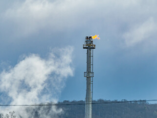 Oil rig burning fire on cloud and mountain background, textured gas prices theme.