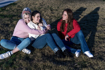 Three young female friends having fun on the city park grass