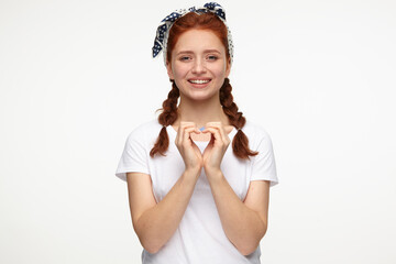 ginger young female smiling and shows love gesture