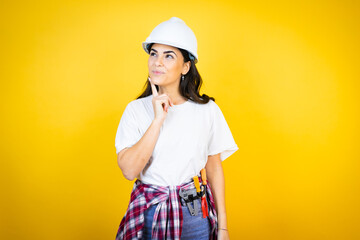Young caucasian woman wearing hardhat and builder clothes over isolated yellow background happy...