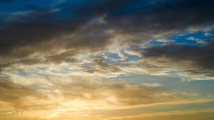 Fototapeta na wymiar Ciel jaunâtre pendant le coucher du soleil. On observe d'esthétiques reflets sous des nuages voilés de haute altitude