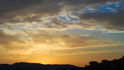 Ciel jaunâtre pendant le coucher du soleil.  On observe d'esthétiques reflets sous des nuages voilés de haute altitude