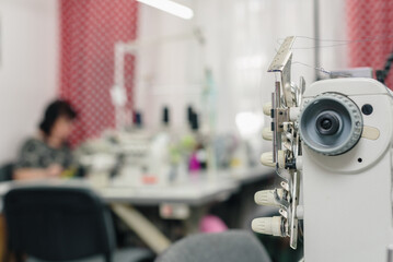 Blurred photo of professional modern dressmaker working on sewing machine