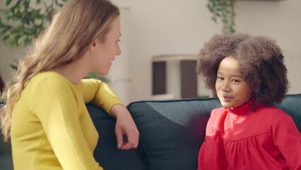 Friendly psychologist communicating with shy little girl, child counseling