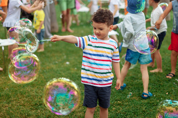 the child inflates large soap bubbles. Street animation program, happy child on a green lawn....
