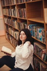 Portrait of young beautiful fashionable lady posing in  library