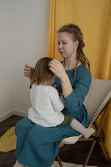 Mom with dreadlocks takes care of the child, sitting on a chair.