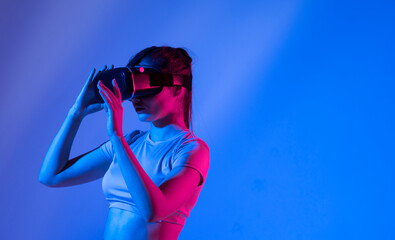 Woman experiencing virtual reality goggles in neon light.