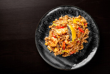 Fried rice with shrimp and vegetables in plate on wooden table background