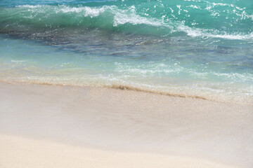 Soft blue oceans wave with foam and clear white sand. Tropical beach by the ocean  