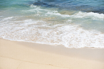 Soft blue oceans wave with foam and clear white sand. Tropical beach by the ocean  