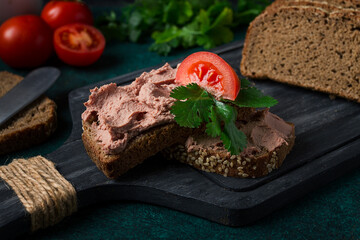 Liver meat pate spread on rye bread, breakfast, close-up, dark background. no people, selective focus,