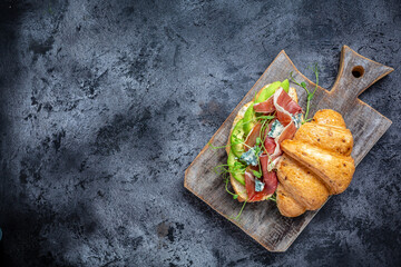 Croissant sandwiches with jamon ham serrano paleta iberica, blue cheese, avocado, microgin on blue...