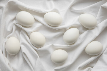 Fototapeta na wymiar Eight white chicken eggs on a linen white cloth with folds. Easter, spring holiday concept.