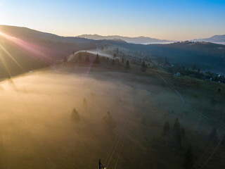 The rays of the morning sun through the fog in the mountains. Aerial drone view.