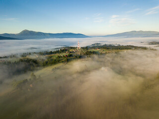 Mountain settlement in the Ukrainian Carpathians in the morning mist. Aerial drone view.