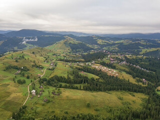 Naklejka premium Green slopes of Ukrainian Carpathian mountains in summer. Cloudy morning, low clouds. Aerial drone view.