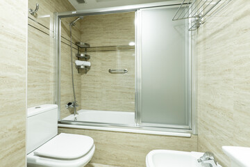 Obraz premium Bathroom with shower cabin with chrome screen, marble tiling and chrome accessories