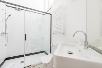 Bathroom with shower cabin with screen with black details, white marble tiling, white electric...