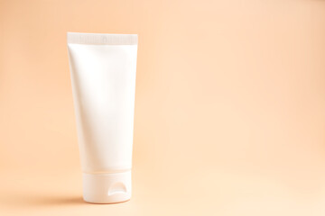 Cream tube on beige background. Cosmetic skincare product blank plastic package. White unbranded lotion, balm, hand cream, toothpaste mockup. Sunscreen cream bottle with copy space
