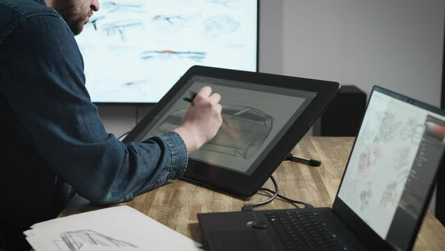 Industrial design studio with graphic tablet and computers. A senior designer draws a new car concept on a tablet.