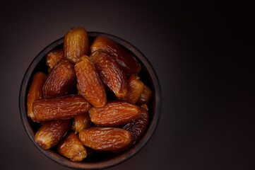 Clay cup full of ripe dried dates top view. Copy space .