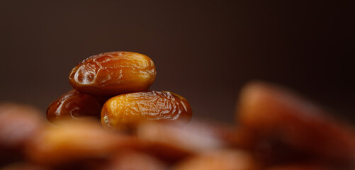 Dates lie on the background of other dates. Ripe dried dates.