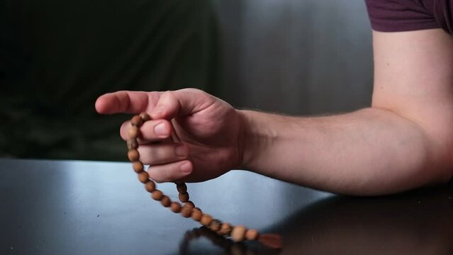 A rosary in a man's hand. Calm, meditation, communion with God.