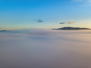 Obraz premium The rays of dawn over the fog in the Ukrainian Carpathians. Aerial drone view.