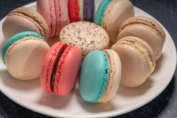 Colorful macarons in white plate on wooden table, Sweet makaron from almond flour and cream.