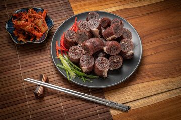 Blood sausage or Sundae in black plate on wooden table background.